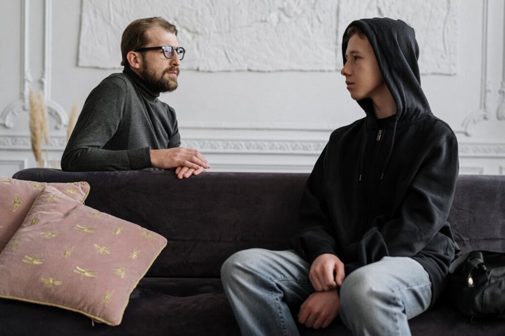 A psychologist and teenager engage in a counseling session in a cozy office setting.